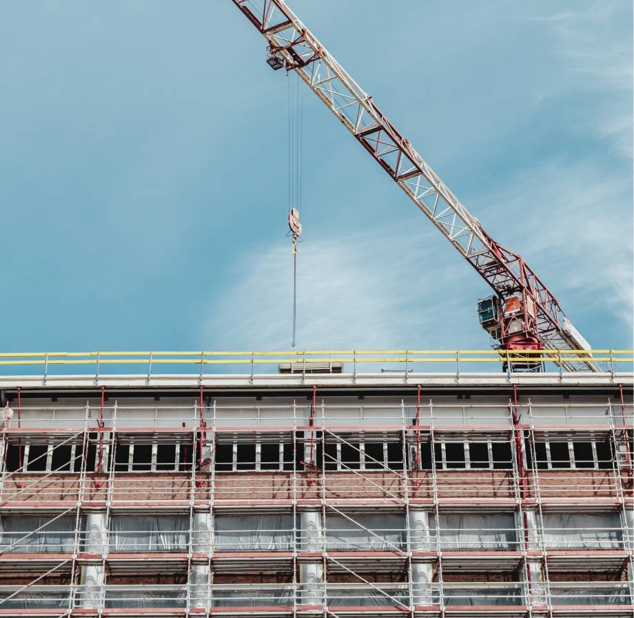 Photo of a tall crane lowering materials on to roof of a building